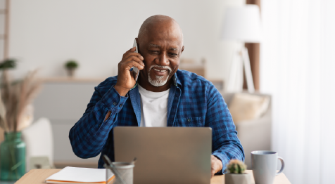 man on computer talking on phone