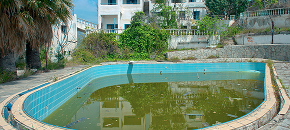 unkept inground pool full of algae water